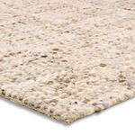 Close-up angled view showing soft, thick wool loops and knit texture in cream and tan tones