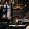 Ambient lit Promenade lamp with green plants and hanging glass pendant lights in background