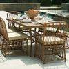 Outdoor dining set of six Cane arm chairs with beige cushions around table near pool