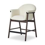 Sora Stool with curved back and armrests, cream boucle upholstery, dark tapered wooden legs and black footrest