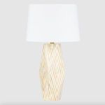 Front view of lamp on beige surface with dark blue background emphasizing its faceted bone inlay base
