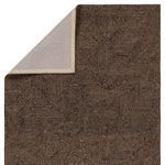 Rug corner folded back to reveal beige fabric backing and stitched edges