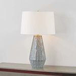 Alloway Table Lamp turned on, mounted on gray surface against light wall, glowing white linen shade