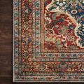 Close-up corner of Layla rug on dark wood floor, highlighting intricate multicolor border with red and teal accents