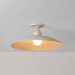 Flush mount viewed from below showing warm glow cast by bulb on the textured plaster shade interior
