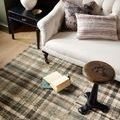 Close-up of Humphrey Forest rug beneath sofa arm and side table with open book on rug