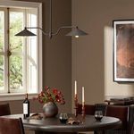 Brecken chandelier in black finish hanging above round dining table with decor and chairs in room setting