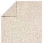Rug flipped to show backside with reversed abstract pattern in cream tones