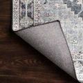 Close-up of Skye Charcoal / Multi Rug corner flipped to reveal textured woven backing on wood floor.