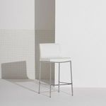 Colter Counter Stool placed in a minimalistic room with white walls and pegboard detail casting shadow