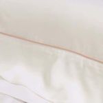 Close-up of soft pink piping detail on smooth bamboo sateen sheet edge