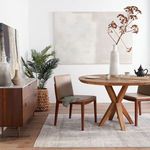 Modern dining area featuring Lavato rug under round wooden table with two brown chairs and decorative vase
