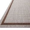Close-up angled view showing flat woven texture and brown border of Easton Dove Coffee Rug