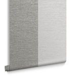 Close-up view of gray and slate vertical stripes on wallpaper, displayed rolled at bottom edge
