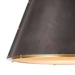 Close-up detail of blackened metal cone texture with brass studs and trimmed brass ring near diffuser