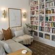 Taylor wall sconces lit in cozy reading nook with sectional sofa, bookshelf, and decorative pillows