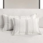 Pair of gray striped shams styled on a light gray bed with a simple headboard in background