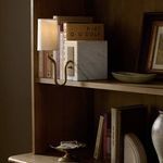 Calla Bookshelf Lamp installed and switched on between books on a wooden bookshelf creating ambient mood lighting