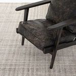 Black wood frame and dark leather seat of armchair on the rug showing color depth contrast
