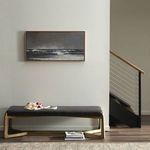 Ocean wave painting hanging on light gray wall above black bench near staircase with wood and metal railing