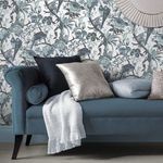Perrow Wallpaper applied on wall behind blue velvet sofa with cushions in neutral shades
