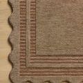 Close-up on rug’s striped border and scalloped edge on light hardwood floor