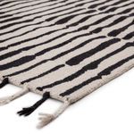 Close-up angled view showing thick wool texture and braided fringes in black and ivory