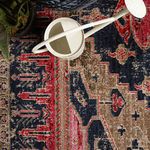 Overhead close-up of rug corner with white metal watering can and plant leaves