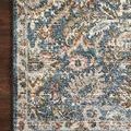 Close-up of rug corner on wood floor highlighting faded blue and sand intricate pattern and finished edge