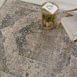 Overhead view of Starling Medallion rug with cream chair and wood round table holding an open book and glasses