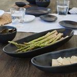 Oval platter filled with fresh asparagus, viewed from above showing depth and textured surface