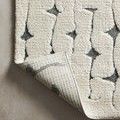 Corner of Hagen Rug folded over revealing the structured weave on its back side.