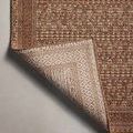 Corner lifted to show detailed woven pattern on the rug's backside in light beige tones