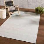 Eliza rug styled indoors with wooden chair, pillow, side table, and plant on hardwood floor