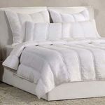 angled front view of quilt on bed with matching pillows, showing smooth texture and plump quilting