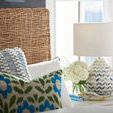 Close-up of Escape Nesting Headboard with wicker texture next to bedside table with lamp and flowers