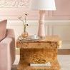 Side table in living room styled with a pink ceramic table lamp and brass sculpture on a light rug