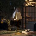 Lamp on wood table with trapezoidal shade lit, showing warm glow in a cozy lounge setting