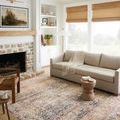 Rug styled in bright living room with sofa, fireplace, and natural light from windows