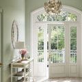Lunaria Orb Chandelier hanging in bright foyer with green walls and large arched windows