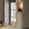 Close-up of Bryce Bath Wall Sconce illuminated beside mirror with gold leaf and crystal frame detail