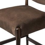 Detail close-up of upholstered seat cushion corner with exposed rounded wooden leg