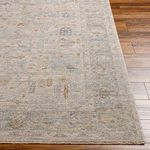 Close-up corner view of light gray woven rug highlighting subtle pattern variations on wooden floor