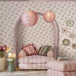 Wallpaper applied in a room setting with arched doorway, striped pink sofa, floral cushions and hanging paper lanterns