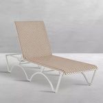 Side angled view of chaise showing curved white aluminum legs and woven wicker surface