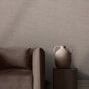 Wallpaper installed on wall behind brown sofa and round side table with ceramic vase