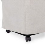 Detail view of black rolling castor wheels beneath light gray upholstered chair skirt