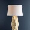Full height side view of lamp against dark blue wall highlighting the tapered drum shade and geometric base