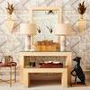 Warwick Mirror shown mounted above raffia-covered console table in styled room with patterned wallpaper and decorative lig...