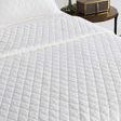 Lana white diamond quilt styled on bed with matching pillow and bedside table
